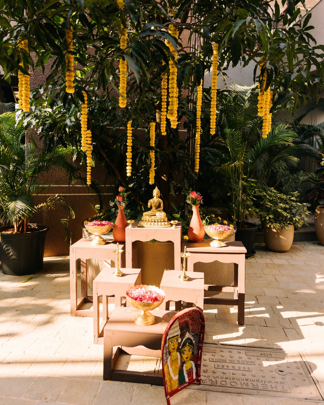 Blush ritual tables beneath hanging marigolds — Gātha