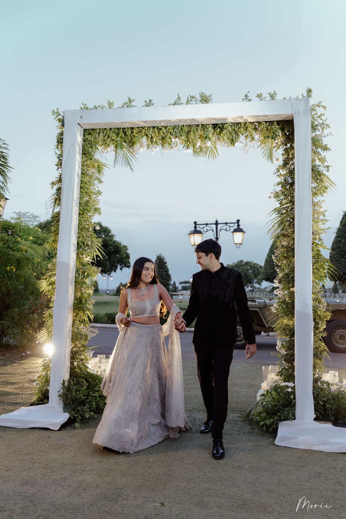 A couple walking through a greenery arch