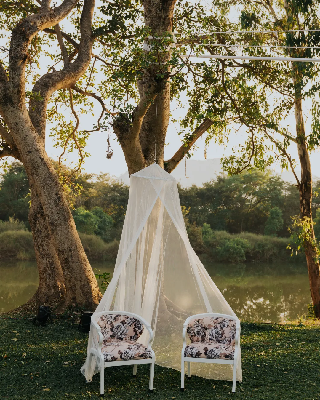 A net canopy and two chairs by the water — Gātha
