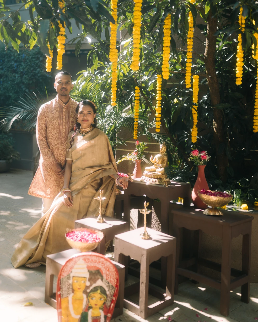 A couple at the ritual table under marigold strings